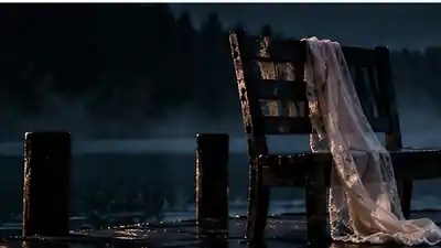 Empty chair with a pale garment on a misty lakeside dock at night